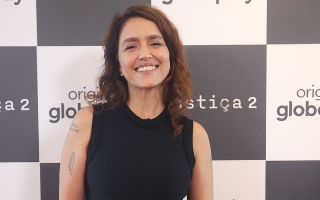 Manuela Dias posa com vestido preto e sorrindo em lançamento da série Justiça 2